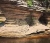A tour boat named Chicagow is navigating between two large rock formations carrying passengers exploring a scenic waterway