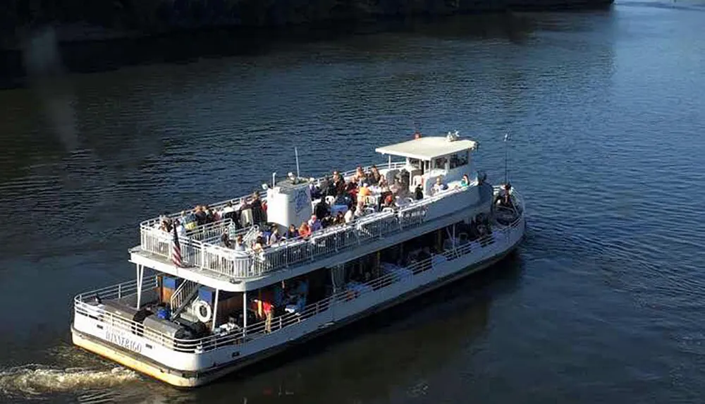 A group of passengers enjoy a sunny outing on a multi-level riverboat named Waterloo