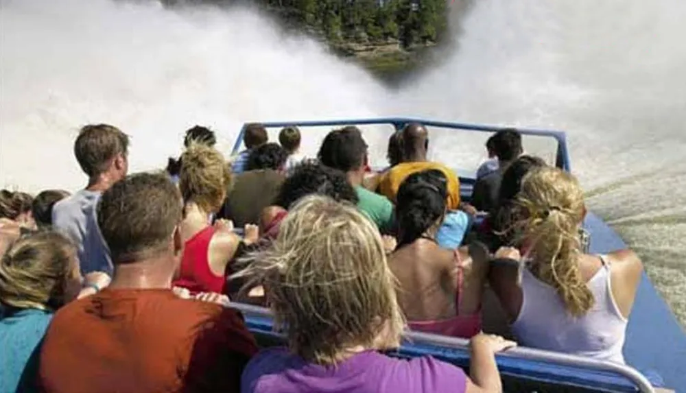A group of thrill-seekers are experiencing an exciting speedboat ride creating a large spray of water behind them