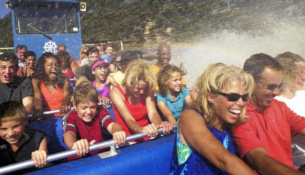 A group of people are joyfully reacting to water spray while riding on a water-themed amusement park attraction