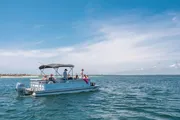 A group of individuals is enjoying a sunny day out on the sea aboard a pontoon boat.