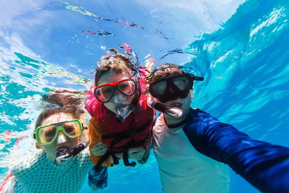 Three people with snorkeling gear are taking a selfie underwater exuding a cheerful adventurous vibe