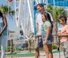 A family is enjoying a scenic view from inside a Ferris wheel gondola with a sunny coastal cityscape stretching out in the background