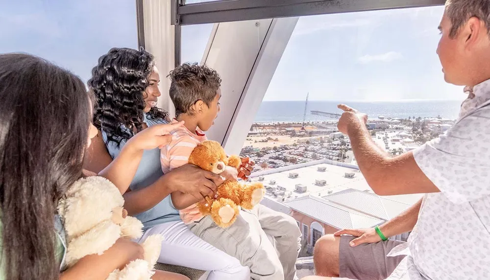 A family is enjoying a scenic view from inside a Ferris wheel gondola with a sunny coastal cityscape stretching out in the background