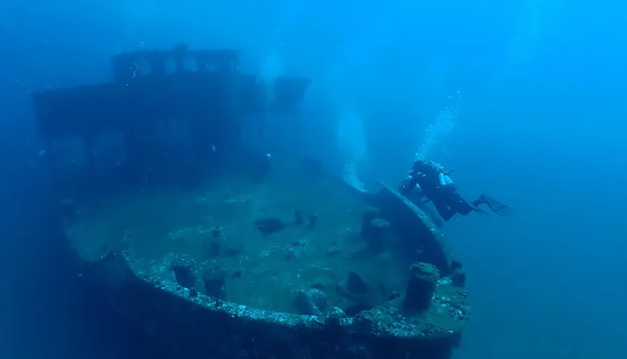 A scuba diver explores the remains of a sunken shipwreck underwater.