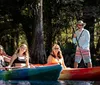 Three people are enjoying a sunny day on the water with colorful kayaks and paddleboards surrounded by a tranquil natural environment