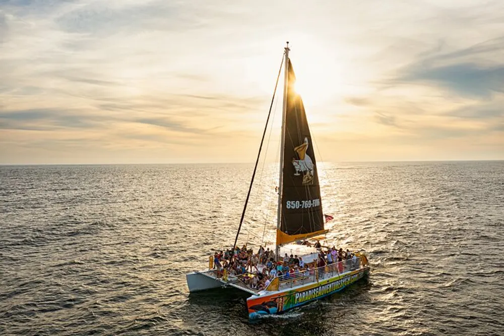 A group of people enjoys a sunset sail on a vibrant catamaran across calm waters