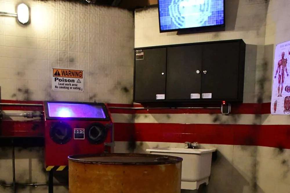 The image shows an industrial or workshop setting with a warning sign for poison a wash basin lockers a television screen and what appears to be an equipment station with purple lighting
