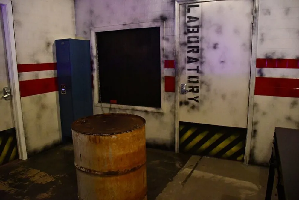 The image shows a dimly lit grimy industrial or laboratory setting with a rusty barrel in the foreground and a door marked LABORATORY with red and white caution stripes