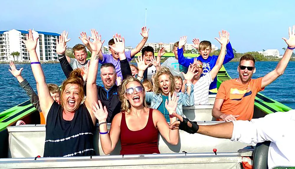 A group of excited people with raised hands is enjoying a boat ride on a sunny day