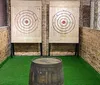 A person is poised to throw an axe at a wooden target in an indoor axe throwing facility