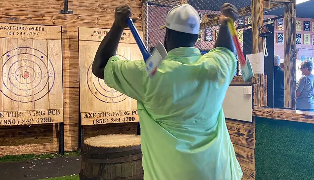 A person is poised to throw an axe at a wooden target in an indoor axe throwing facility