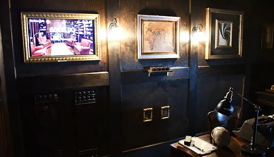 The image shows a dark, moody room styled with a vintage aesthetic, featuring an ornate desk with a lamp and globe, walls adorned with framed artwork and wall sconces, and a television displaying a luxurious interior scene.