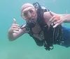 A scuba diver is making a hand signal underwater with text overlay promoting free GoPro videos and pictures