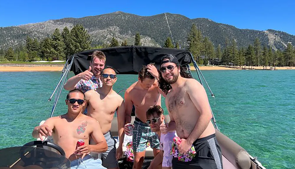 A group of people is enjoying a sunny day aboard a boat with clear turquoise waters and a mountainous backdrop