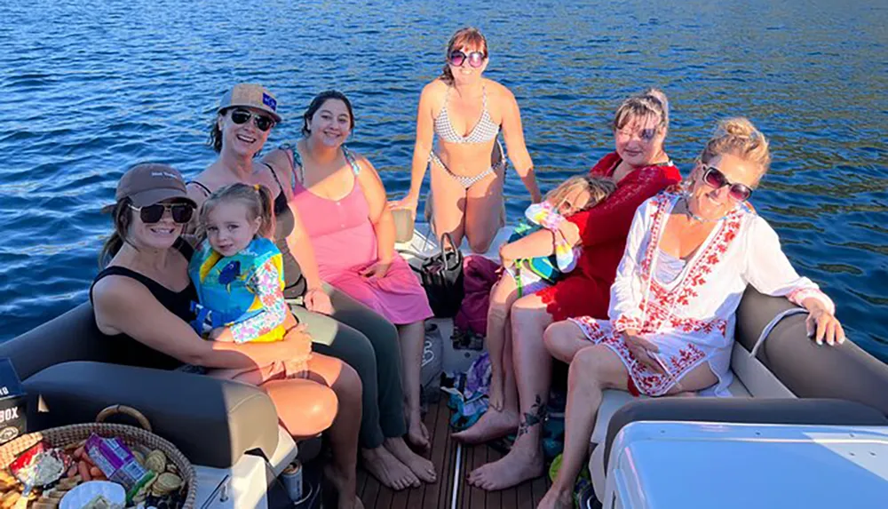 A group of happy people predominantly women and children are enjoying a sunny day on a boat with a clear blue water backdrop