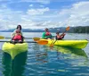 Four individuals are enjoying kayaking on a calm lake with a picturesque mountainous backdrop