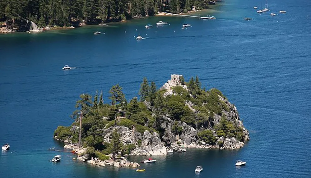 A small rocky island with trees and a stone structure on top is surrounded by clear blue water with boats nearby
