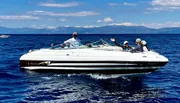 A group of people is enjoying a bright sunny day out on the water in a speeding motorboat.