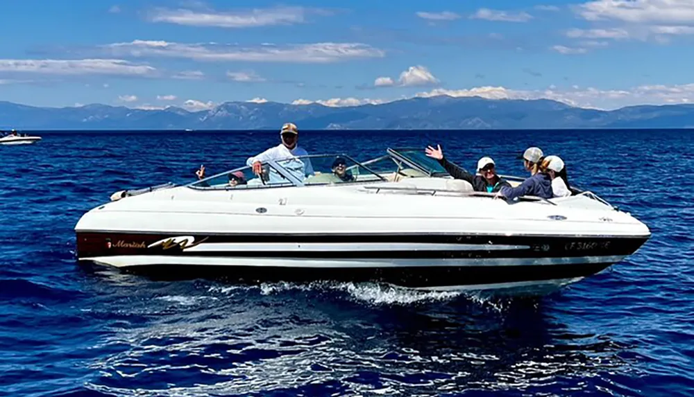 A group of people is enjoying a bright sunny day out on the water in a speeding motorboat
