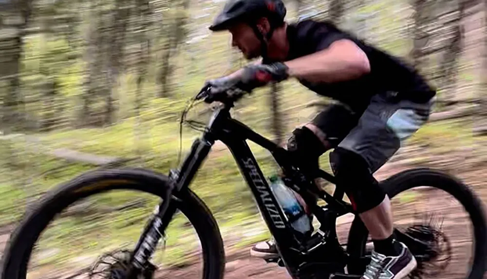 A mountain biker in motion wearing protective gear is intensely focusing on the trail ahead