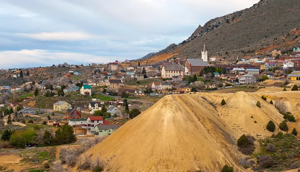 The image showcases a panoramic view of a small town nestled in a hilly landscape with prominent church spires colorful houses and a large barren hill in the foreground