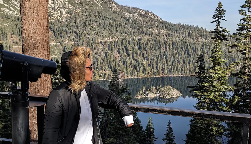 A person is enjoying a scenic view of a tranquil mountain lake surrounded by forested slopes