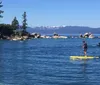 Four people are paddleboarding on a calm lake with a backdrop of a lakeside community and forested hills