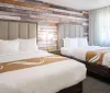 A modern hotel room with two double beds featuring a rustic wood plank accent wall and soft natural lighting from the window