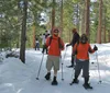 Four individuals are posing with smiles and trekking poles on a snow-covered slope during what appears to be a winter hiking excursion