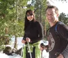 Four individuals are posing with smiles and trekking poles on a snow-covered slope during what appears to be a winter hiking excursion