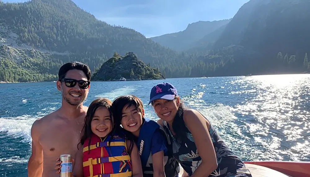 A family is smiling and enjoying a sunny day on a boat with a scenic mountainous backdrop
