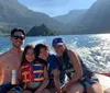 A family is smiling and enjoying a sunny boat ride on a scenic lake with mountains in the background