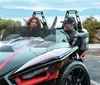 Two individuals are enjoying a ride in a Polaris Slingshot against a backdrop of nature