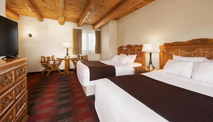 A cozy hotel room with twin beds rustic wooden furniture and a warm color scheme