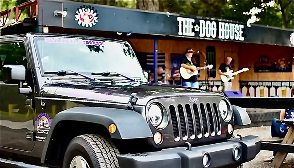 A Jeep is parked in front of a venue named THE DOG HOUSE where a live music performance is taking place