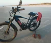 An electric bicycle is parked on a sandy beach with a pair of flip-flops placed beside it as the sun sets suggesting a leisurely pause in someones ride