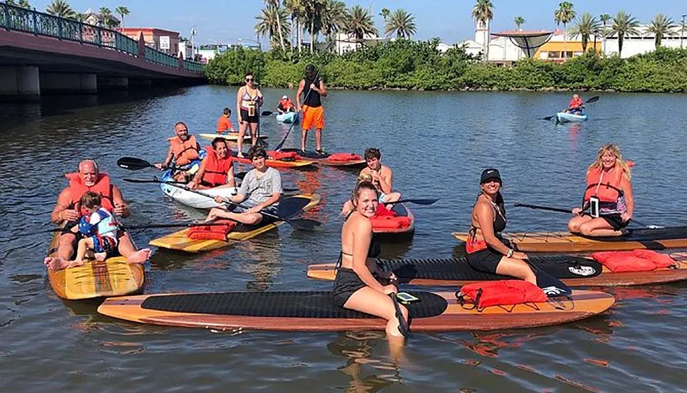 A group of people in life jackets are enjoying a sunny day on stand-up paddle boards in a calm waterway