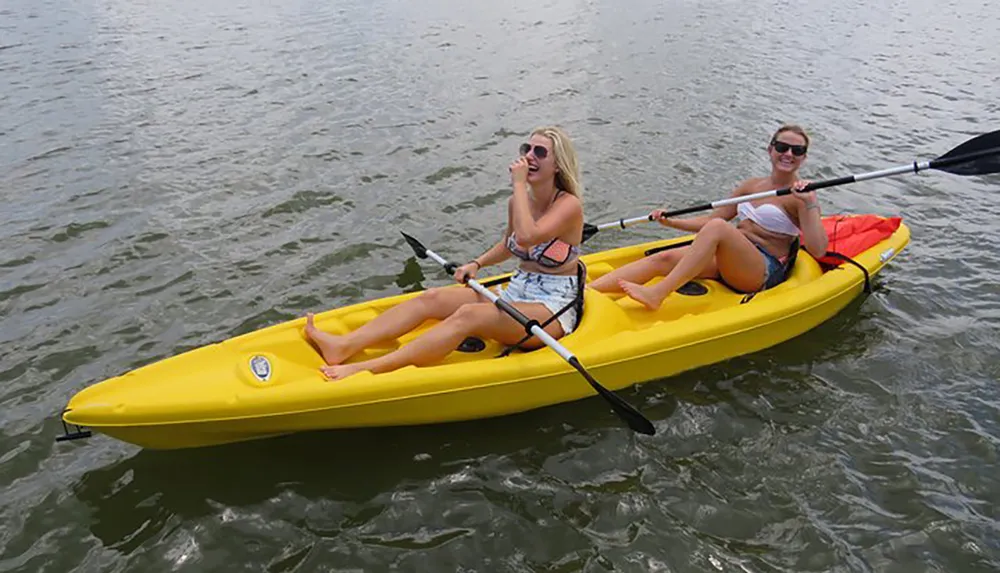 Two people are enjoying paddling in a yellow kayak on a body of water