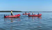 Several people are enjoying a sunny day on the water with their inflatable boats.