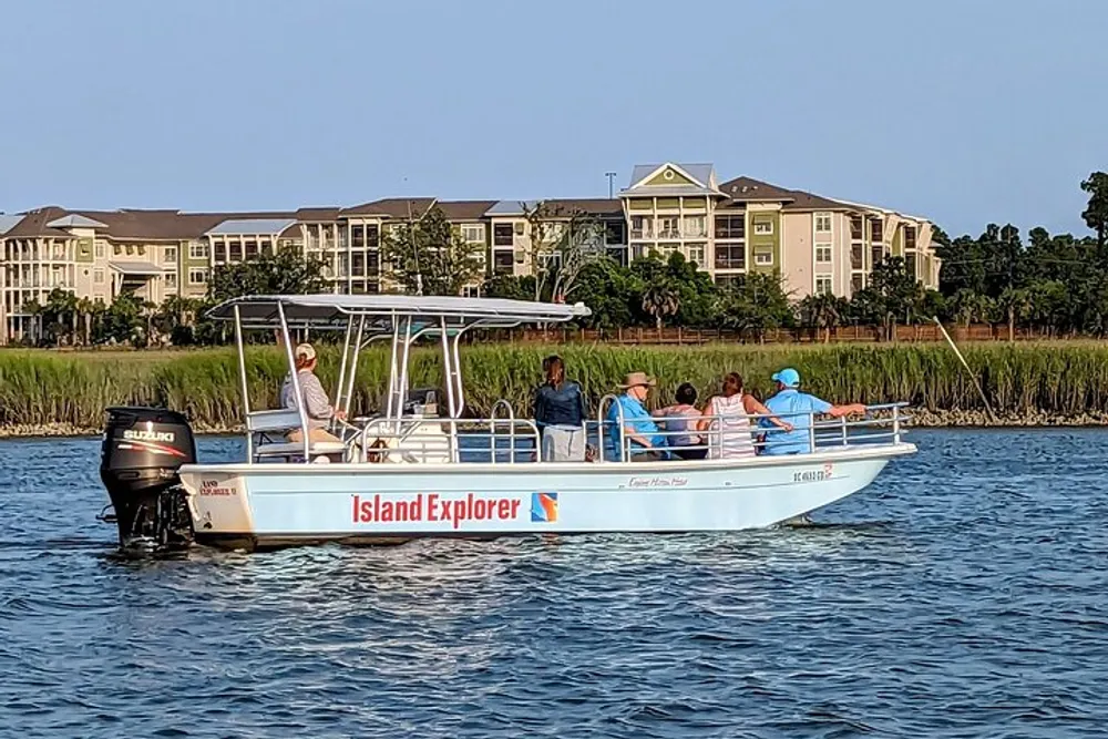 A group of people enjoy a serene boat ride on a calm waterway near a coastal housing development