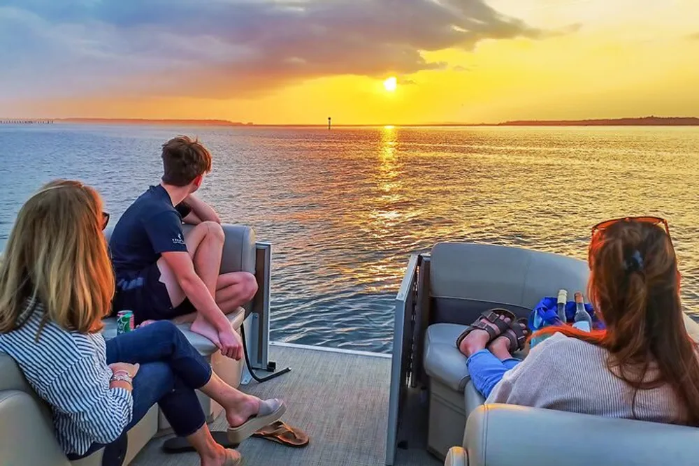 A group of people is enjoying a sunset view from the back of a boat