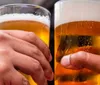 Two hands are holding glasses of beer likely symbolizing a social gathering or a toast