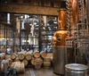 The image shows an interior view of a distillery with copper stills and aging barrels highlighting the production process of spirits such as whiskey