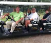 A group of people is smiling for a photo while seated in a multi-passenger golf cart labeled Pat Conroys Beaufort Tour on what looks like a guided tour