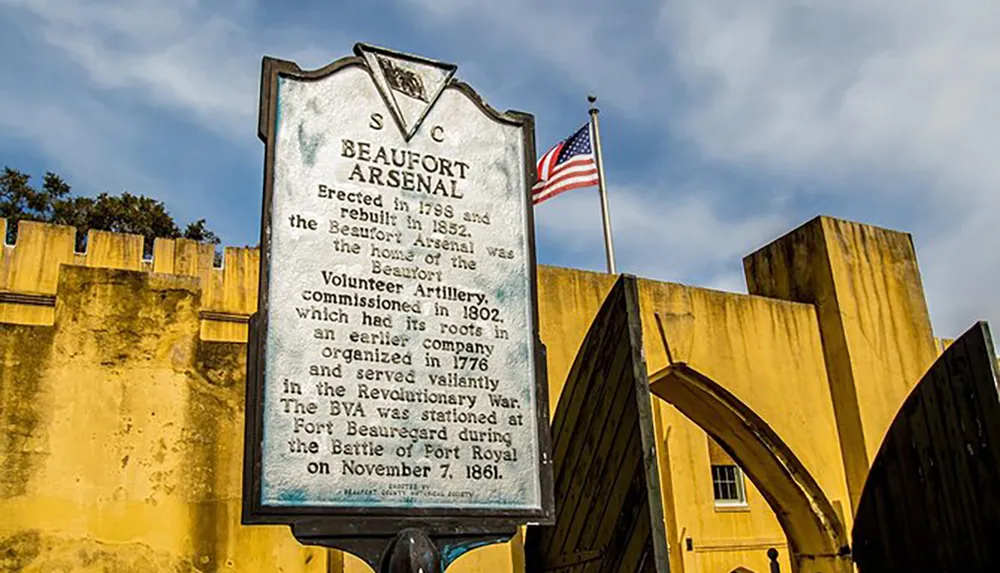 The image shows a historical marker denoting the Beaufort Arsenal along with an American flag and what appears to be part of the arsenals yellow-colored walls or battlements in the background