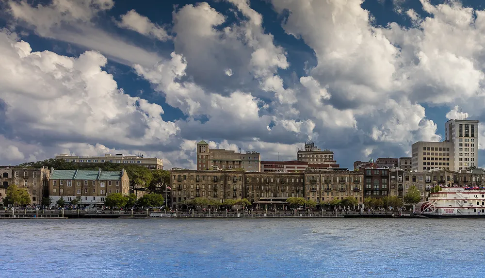 The image features a scenic riverside view with historic buildings against a backdrop of dramatic clouds in the sky