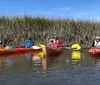 A group of smiling people in life jackets are enjoying a sunny day while kayaking on calm waters surrounded by tall reeds