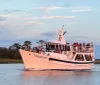 A group of people enjoy a scenic boat ride on a vessel named Vagabond as two dolphins leap from the water nearby