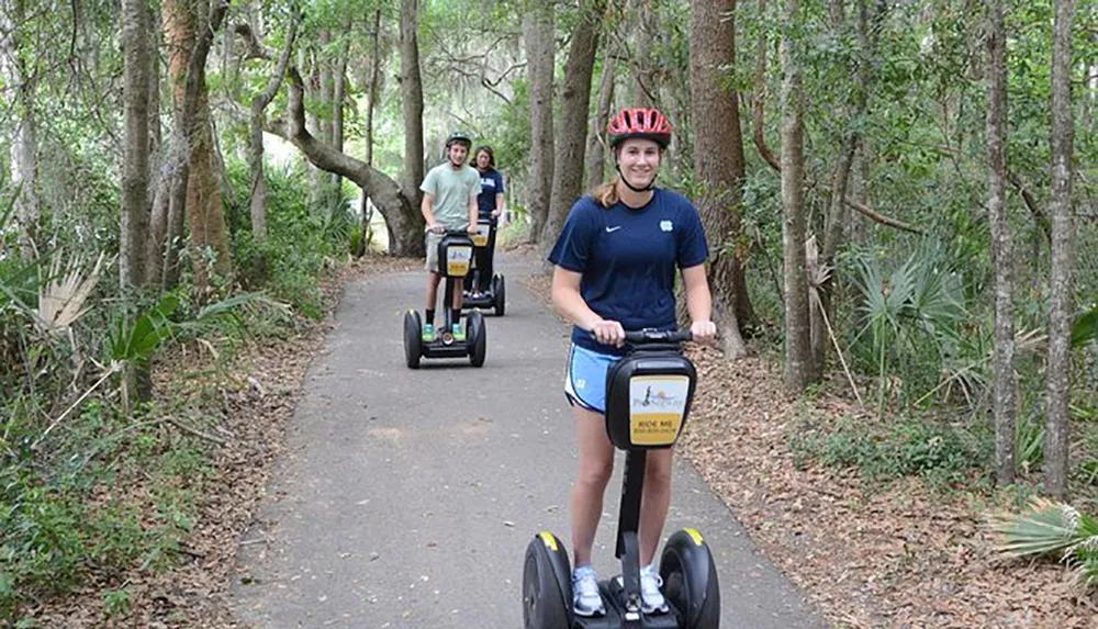 A group of people is enjoying a Segway tour along a tree-lined path